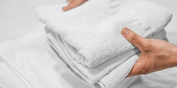 Hands holding a freshly laundered stack of white Egyptian cotton towels for Jersey Shore vacation rental
