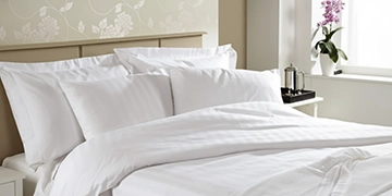 Freshly made vacation rental bed dressed in white Egyptian cotton sheets, pillowcases and a comforter